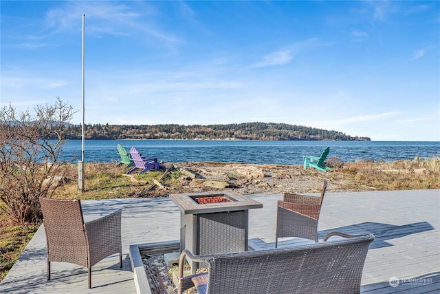 view of patio with a deck with water view and a fire pit