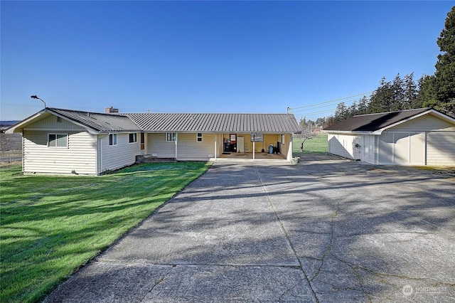 view of front of property with a garage, an outdoor structure, and a front lawn