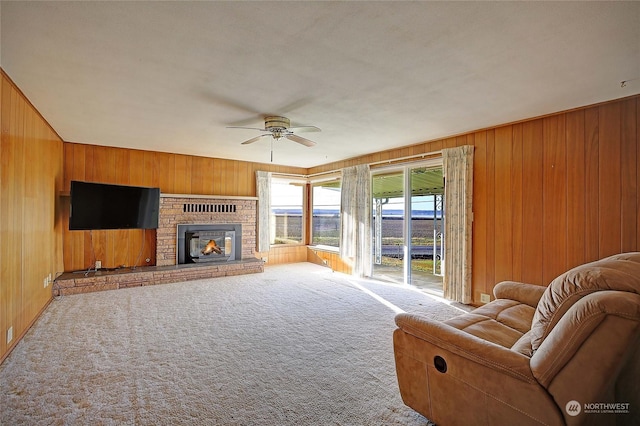 living room featuring ceiling fan, carpet flooring, a fireplace, and wooden walls