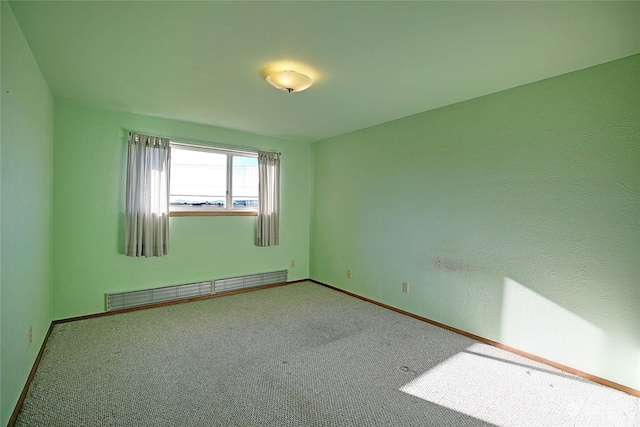 spare room with a baseboard heating unit and carpet flooring