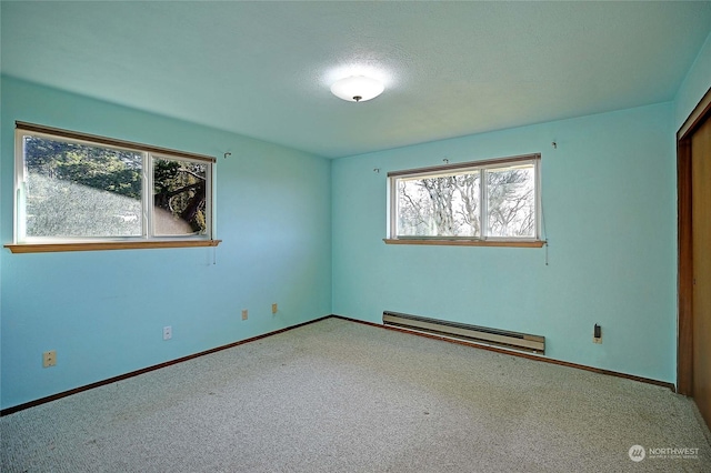 carpeted spare room featuring a baseboard heating unit