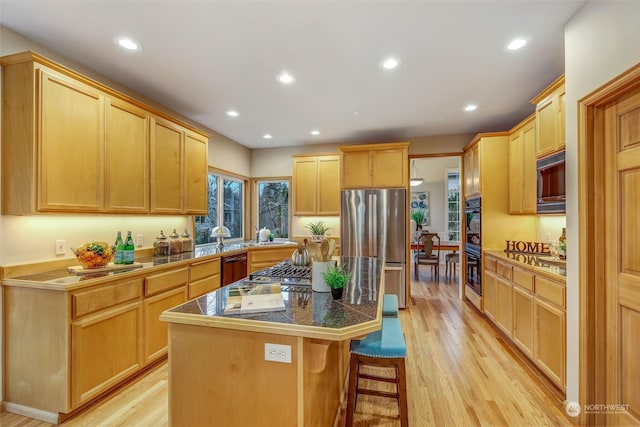 kitchen with stainless steel refrigerator, a kitchen bar, a center island, and light brown cabinets