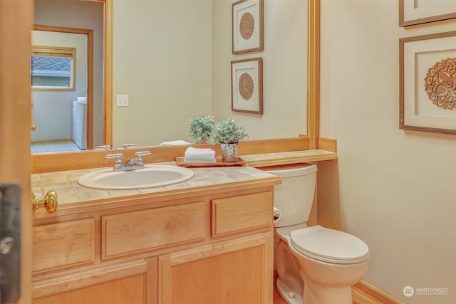 bathroom featuring vanity, toilet, and washer / dryer