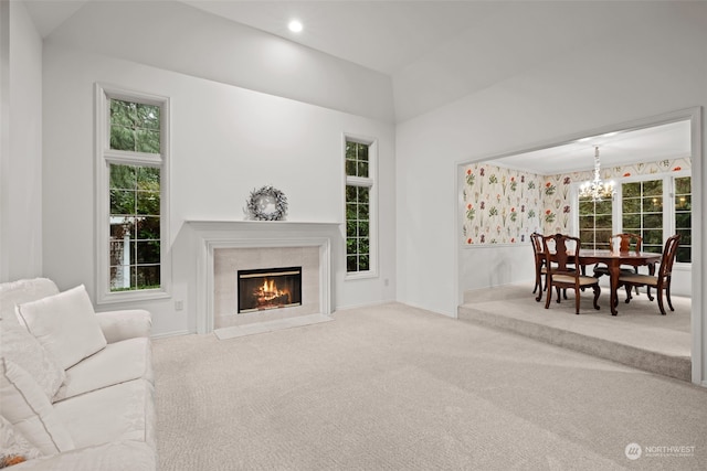 living room featuring carpet, a healthy amount of sunlight, and an inviting chandelier