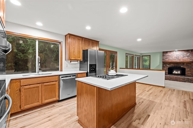 kitchen with sink, a center island, light hardwood / wood-style flooring, stainless steel appliances, and a fireplace