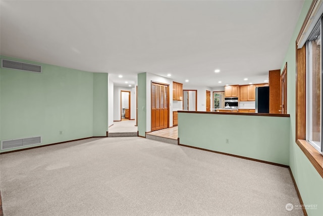 unfurnished living room with light colored carpet