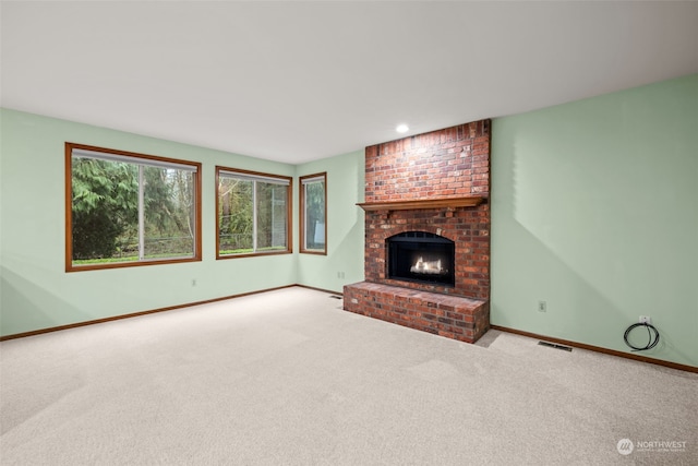 unfurnished living room featuring a brick fireplace and light colored carpet