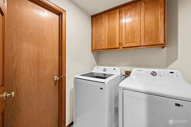 clothes washing area with cabinets and washer and dryer