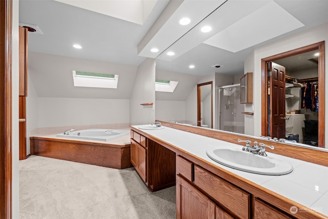 bathroom with vanity, vaulted ceiling with skylight, and separate shower and tub