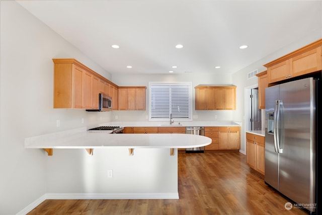 kitchen with sink, a breakfast bar area, stainless steel appliances, and kitchen peninsula