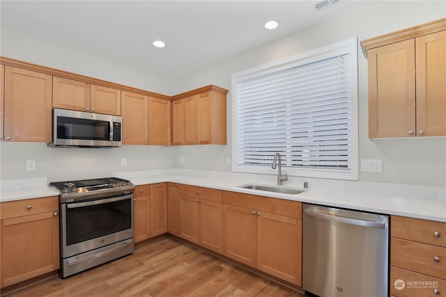 kitchen with appliances with stainless steel finishes, light hardwood / wood-style floors, and sink