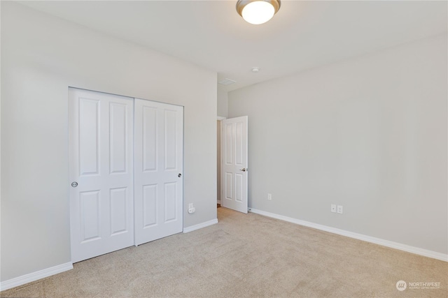 unfurnished bedroom featuring light carpet and a closet