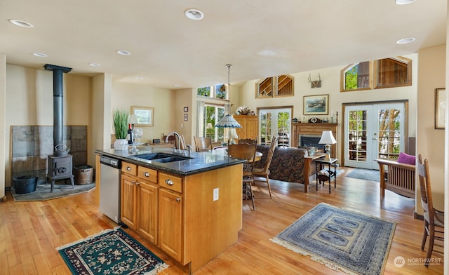 kitchen with pendant lighting, sink, stainless steel dishwasher, a center island with sink, and french doors