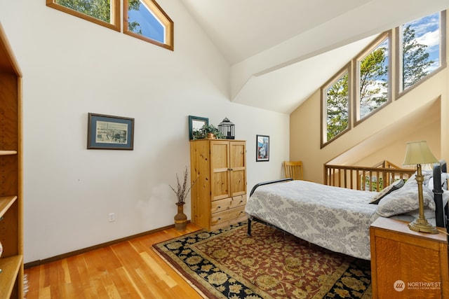 bedroom featuring wood-type flooring and high vaulted ceiling