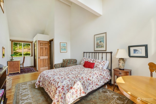 bedroom with high vaulted ceiling and hardwood / wood-style floors