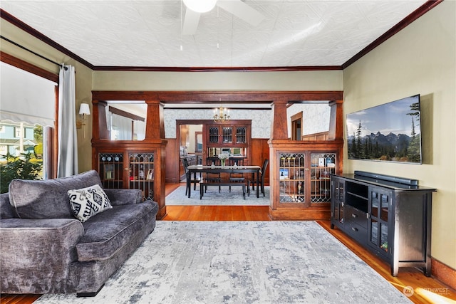 living room with wood-type flooring, ornamental molding, and ceiling fan