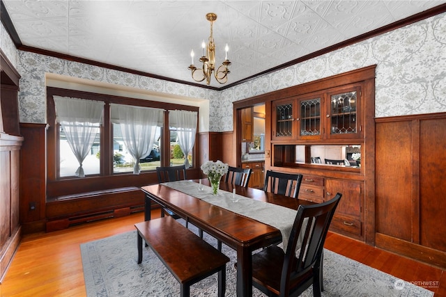 dining space featuring ornamental molding, light wood-type flooring, and an inviting chandelier