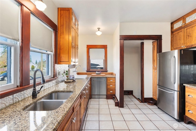 kitchen with sink, backsplash, stainless steel appliances, and light stone countertops