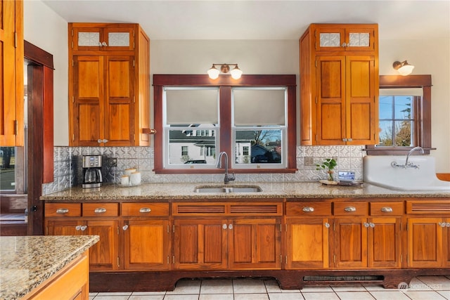 kitchen with light stone counters, light tile patterned flooring, sink, and tasteful backsplash