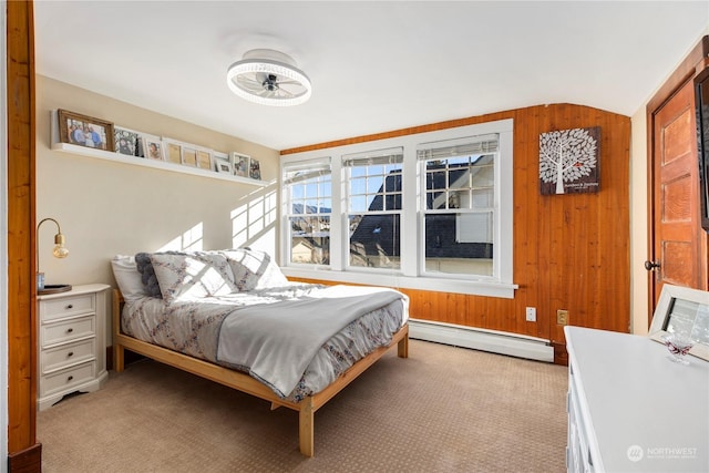 carpeted bedroom with a baseboard radiator, lofted ceiling, and wooden walls