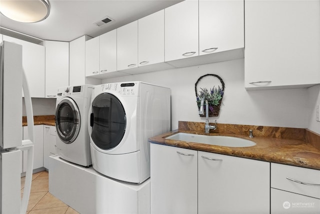 washroom featuring cabinets, sink, light tile patterned floors, and washing machine and clothes dryer