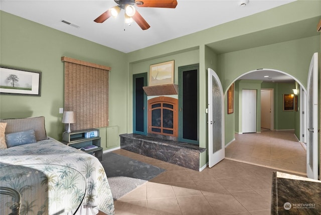 bedroom featuring ceiling fan, light tile patterned floors, and a high end fireplace