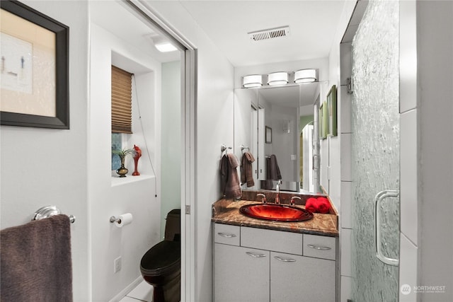 bathroom featuring vanity, an enclosed shower, and toilet