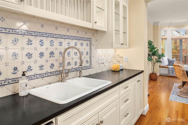 kitchen featuring white cabinetry, light hardwood / wood-style floors, sink, and backsplash