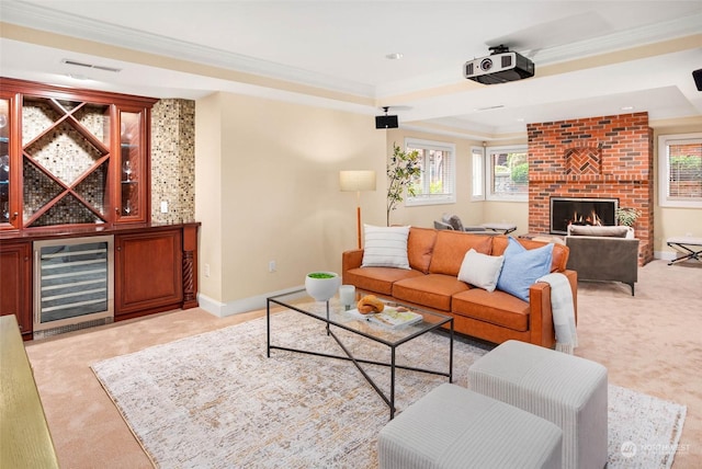 living room with a brick fireplace, light colored carpet, beverage cooler, and a tray ceiling