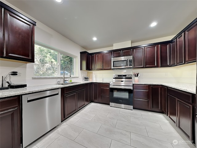 kitchen with light stone counters, sink, and stainless steel appliances