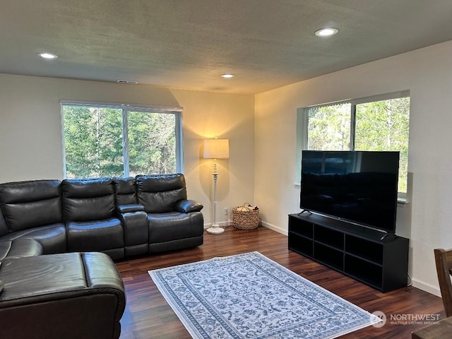 living room with dark wood-type flooring, plenty of natural light, and a textured ceiling