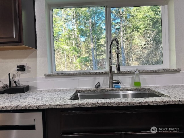 interior details featuring dark brown cabinetry, sink, light stone countertops, and beverage cooler