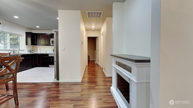 kitchen featuring dark brown cabinetry, stainless steel electric stove, light hardwood / wood-style floors, and sink