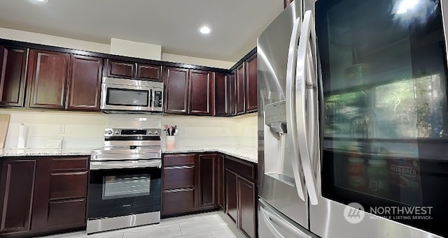 kitchen featuring light stone counters, light tile patterned floors, and stainless steel appliances