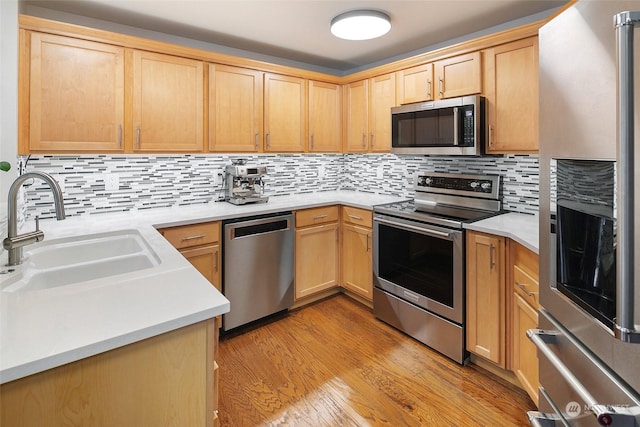 kitchen with sink, light hardwood / wood-style flooring, appliances with stainless steel finishes, backsplash, and light brown cabinetry