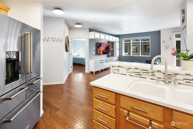 kitchen featuring high end fridge, sink, backsplash, and dark hardwood / wood-style floors