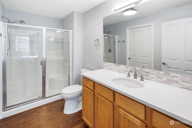 bathroom with tasteful backsplash, vanity, wood-type flooring, toilet, and walk in shower