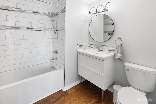 full bathroom featuring wood-type flooring, decorative backsplash, tiled shower / bath combo, vanity, and toilet