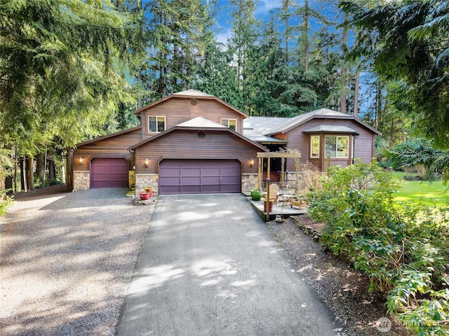 split level home with a garage, stone siding, and driveway