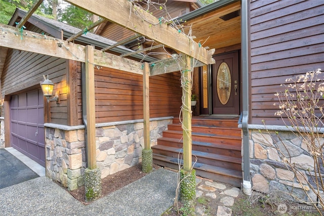 entrance to property featuring a garage and stone siding