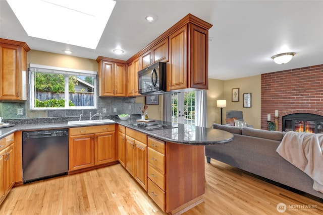 kitchen with a peninsula, a sink, open floor plan, brown cabinets, and black appliances