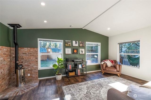 living area with lofted ceiling, dark hardwood / wood-style flooring, a healthy amount of sunlight, and a wood stove