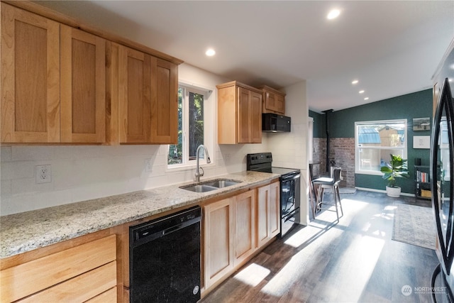 kitchen with sink, light stone counters, pendant lighting, hardwood / wood-style floors, and black appliances