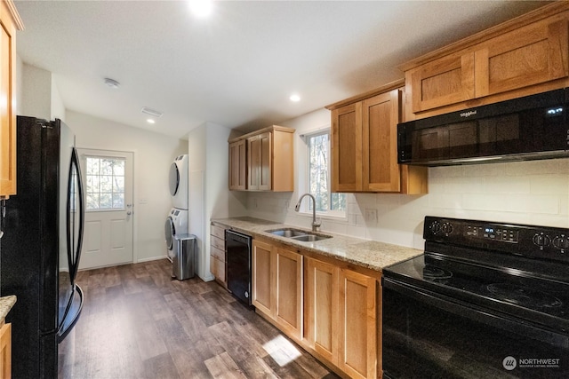 kitchen featuring sink, backsplash, dark hardwood / wood-style floors, stacked washer / dryer, and black appliances