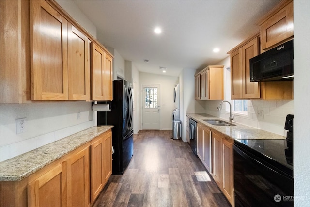 kitchen with sink, tasteful backsplash, stacked washer / dryer, light stone countertops, and black appliances