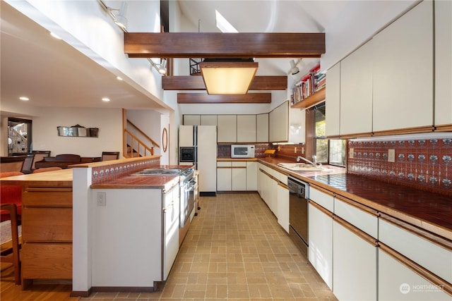 kitchen with sink, white appliances, white cabinetry, tasteful backsplash, and beamed ceiling