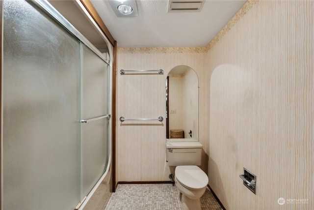 bathroom with toilet and a shower with door