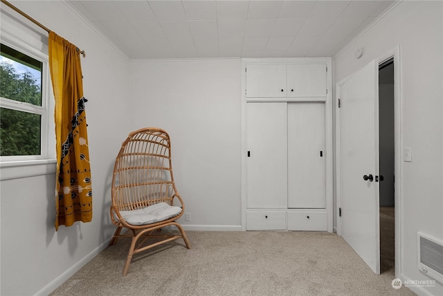 sitting room with ornamental molding and light colored carpet