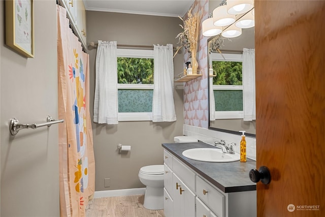 bathroom featuring toilet, crown molding, vanity, hardwood / wood-style floors, and decorative backsplash