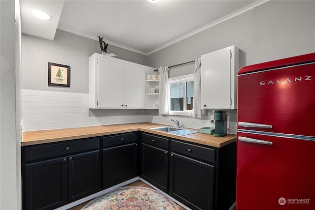 kitchen featuring butcher block counters, sink, white cabinetry, refrigerator, and ornamental molding